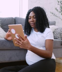 Bereid je voor op de bevalling, een zwarte zwangere zit in een boek te lezen.