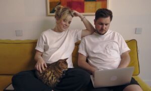 een zwangere en haar partner zitten op de bank met de laptop op hun schoot.