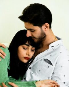 een zwangere leunt op de borst van haar partner, met haar ogen dicht